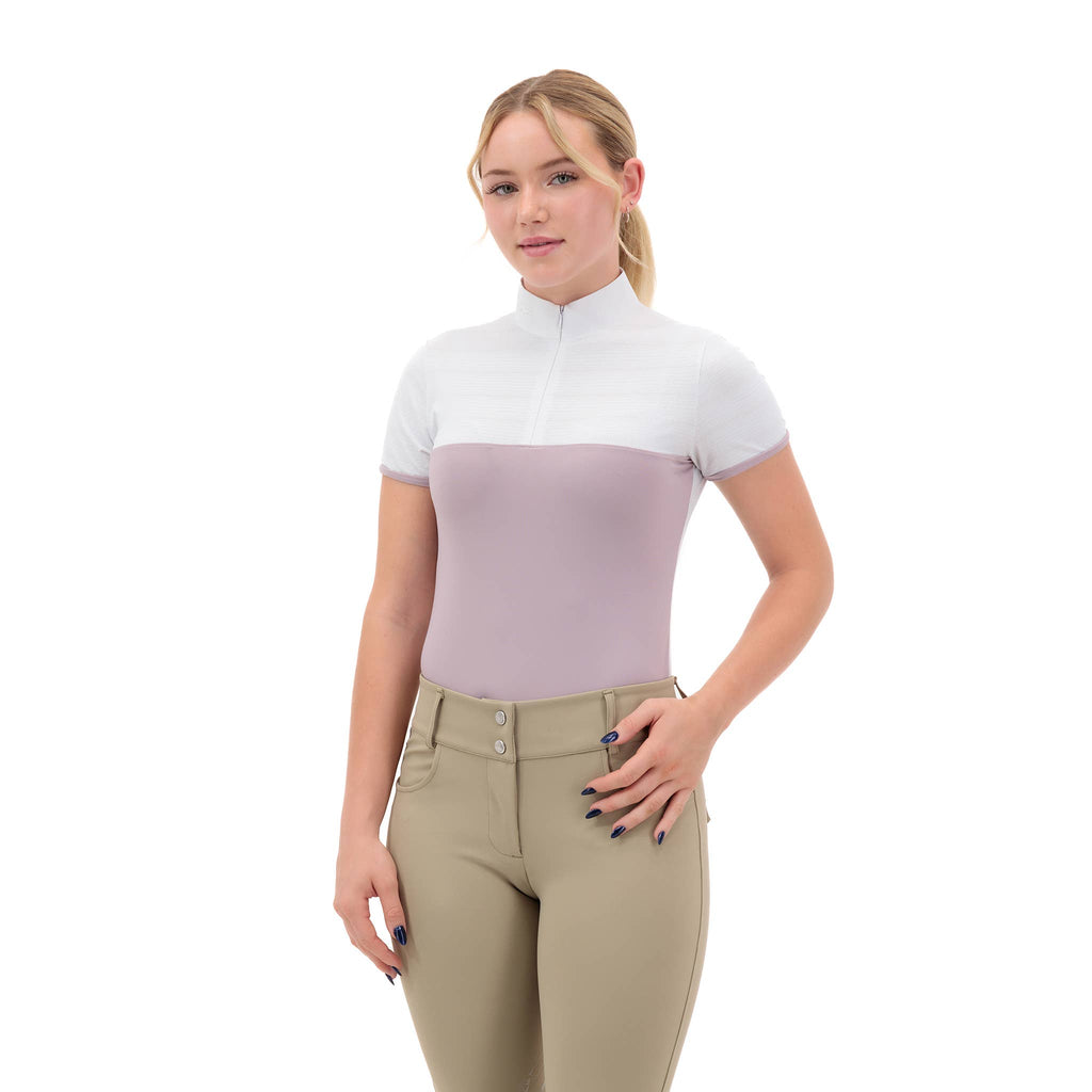 Woman wearing a two-tone equestrian shirt in mauve pink and beige riding tights on a white background